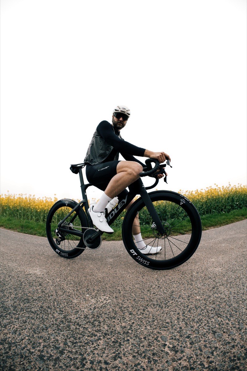 Nick fährt mit dem Rennrad an einem Rapsfeld entlang
