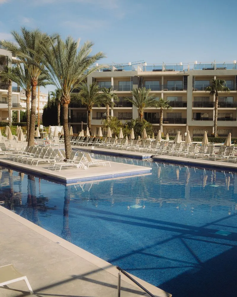 Hauptpool des Zafiro Palace Alcúdia mit Palmen, Sonnenliegen und Hotelgebäude
