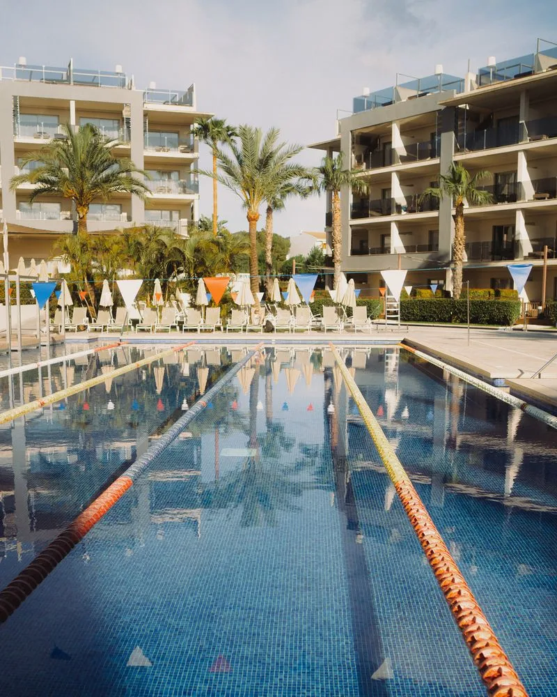 Sportpool des Zafiro Palace Alcúdia mit Bahnleinen, dahinter Palmen und Hotelgebäude