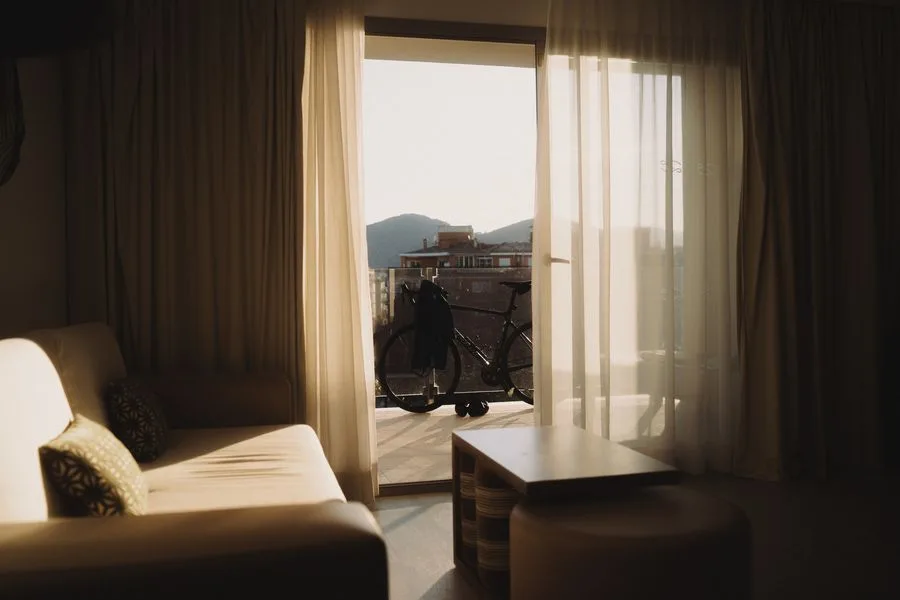 Hotelzimmer mit Sofa und Balkon, auf dem ein Rennrad steht, Blick auf die Berge