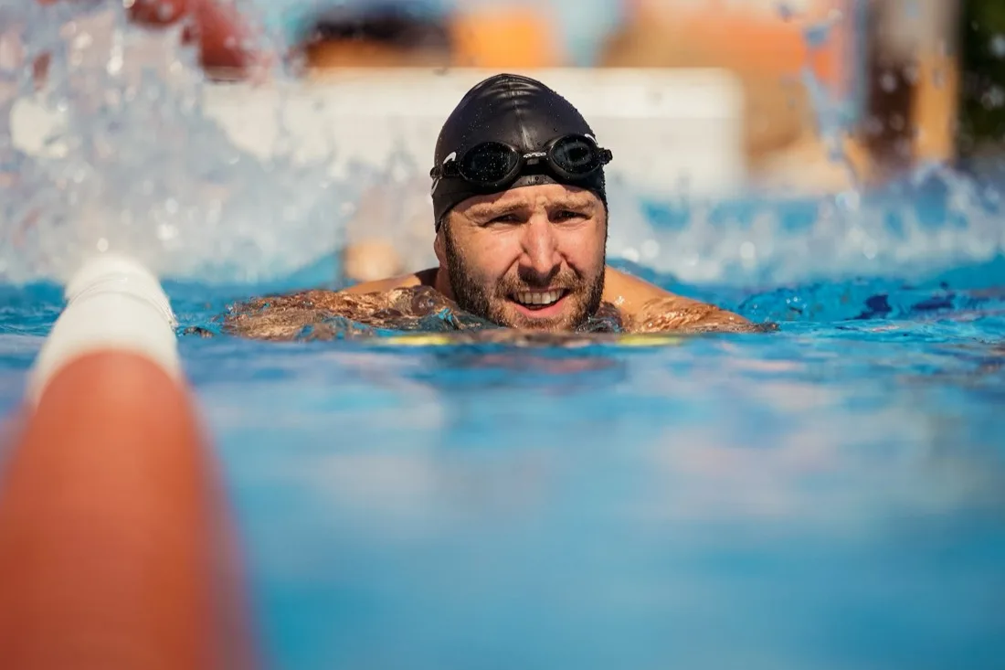 Nick schwimmt im Freibad und schaut nach vorn