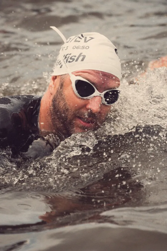 Nick schwimmt im Freiwasser, Nahaufnahme mit Badekappe und Schwimmbrille