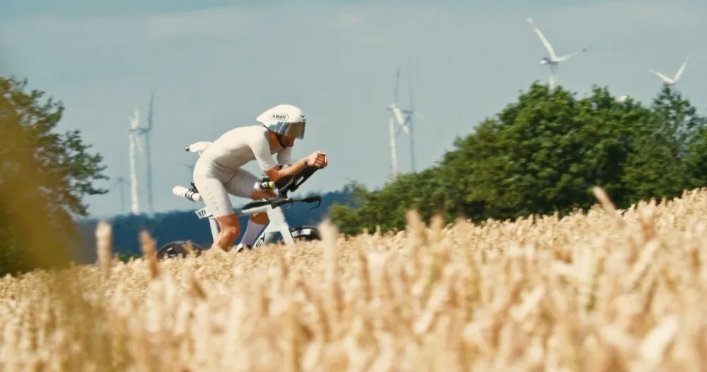 Nick auf dem Zeitfahrrad bei der Challenge Roth 2026, vorne ein Weizenfeld, hinten Windräder