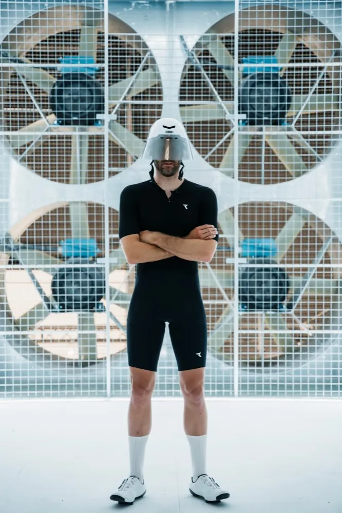 Nick mit verschränkten Armen vor den Ventilatoren eines Windkanals