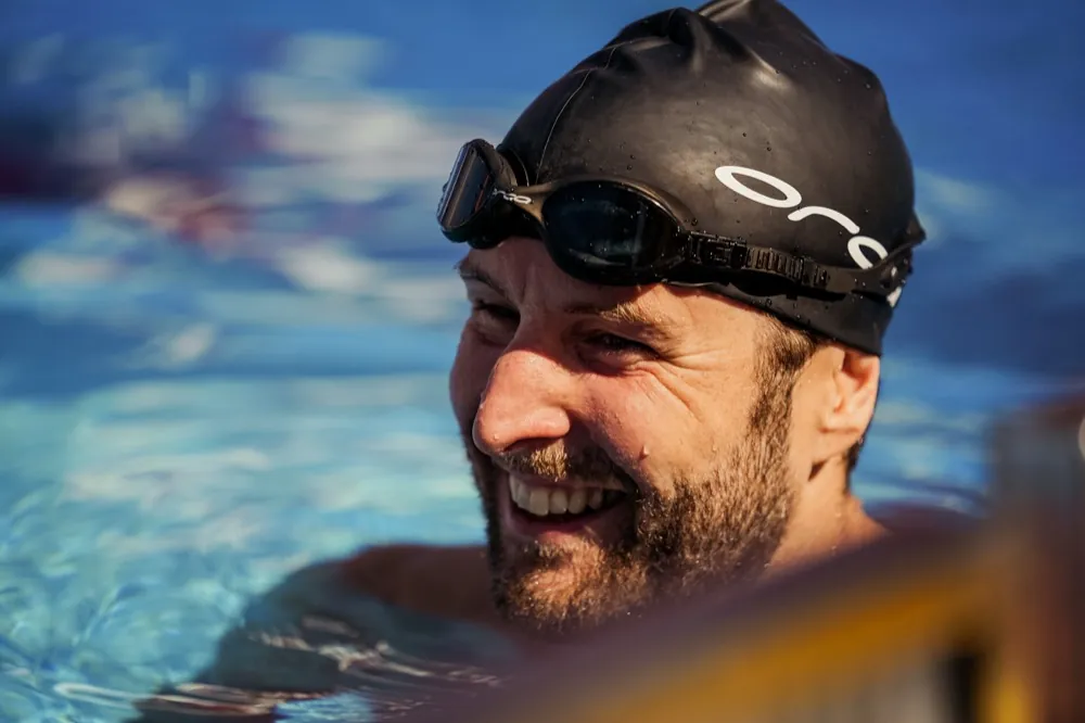 Nick lacht im Wasser, die Schwimmbrille auf der Badekappe