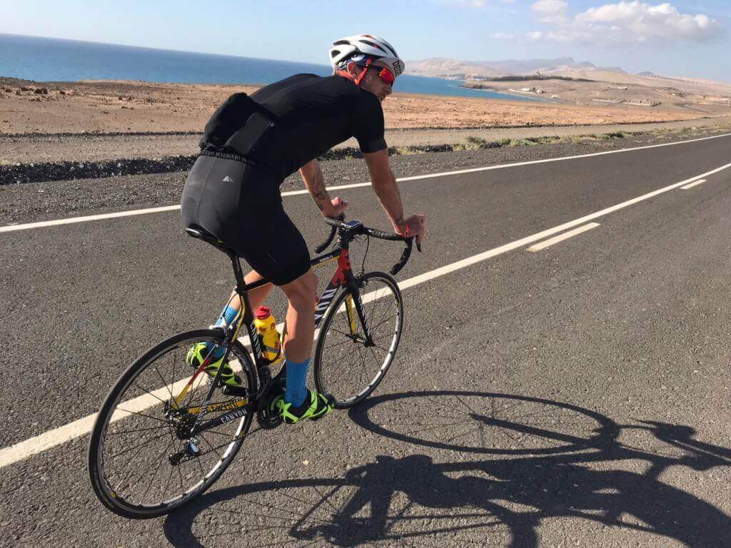 Niclas Bock beim Radtraining auf einer Küstenstraße auf Fuerteventura, im Hintergrund das Meer