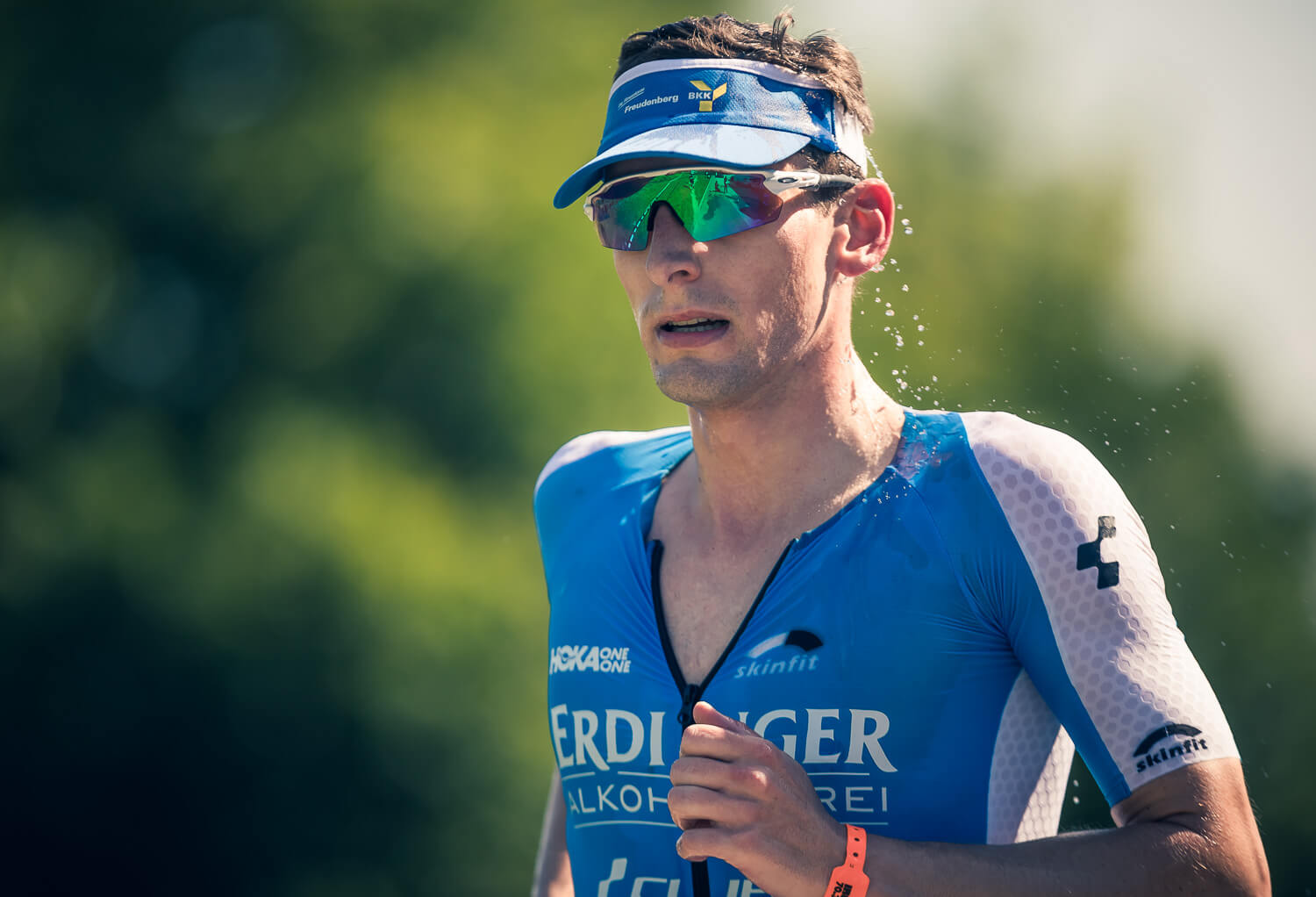 Triathlet im blauen Erdinger-Einteiler mit Visor und grün verspiegelter Brille beim Laufen, Ironman 70.3 St. Pölten 2018