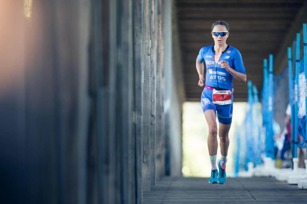 Triathletin mit Startnummer 1 läuft beim IRONMAN 70.3 St. Pölten 2018 durch einen überdachten Holzgang