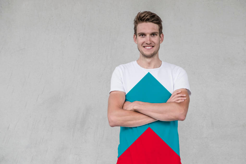 Incylence-Gründer Alex Siegmund lächelt mit verschränkten Armen vor einer grauen Betonwand