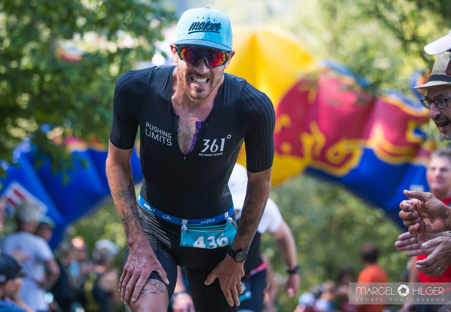 Niclas Bock stützt sich am steilen Kuhsteig beim Allgäu Triathlon auf die Oberschenkel, Zuschauer feuern ihn an