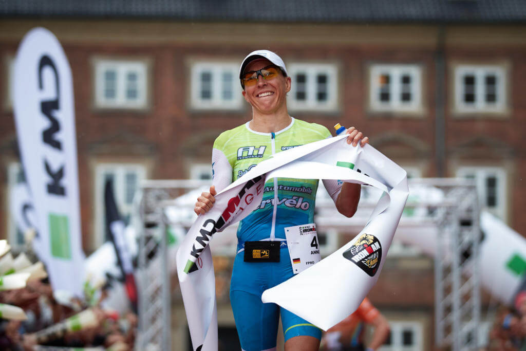 Anne Haug läuft lächelnd mit dem Zielband über die Ziellinie des Ironman Copenhagen