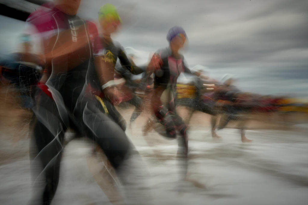 Profi-Triathletinnen laufen beim Ironman Barcelona 2018 in Calella zum Schwimmstart ins Meer, Aufnahme mit Bewegungsunschärfe