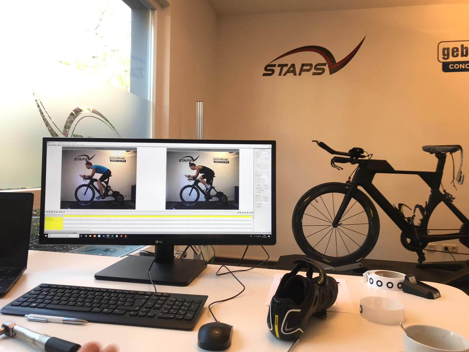 Bikefitting bei STAPS in Köln: Monitor mit Seitenansichten eines Radfahrers, daneben ein Zeitfahrrad