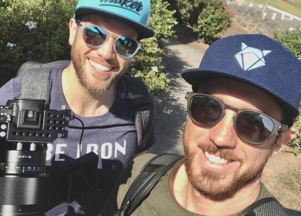 Selfie von zwei lachenden Männern mit Kappen und Sonnenbrillen im Trainingslager auf Fuerteventura, einer mit Kamera
