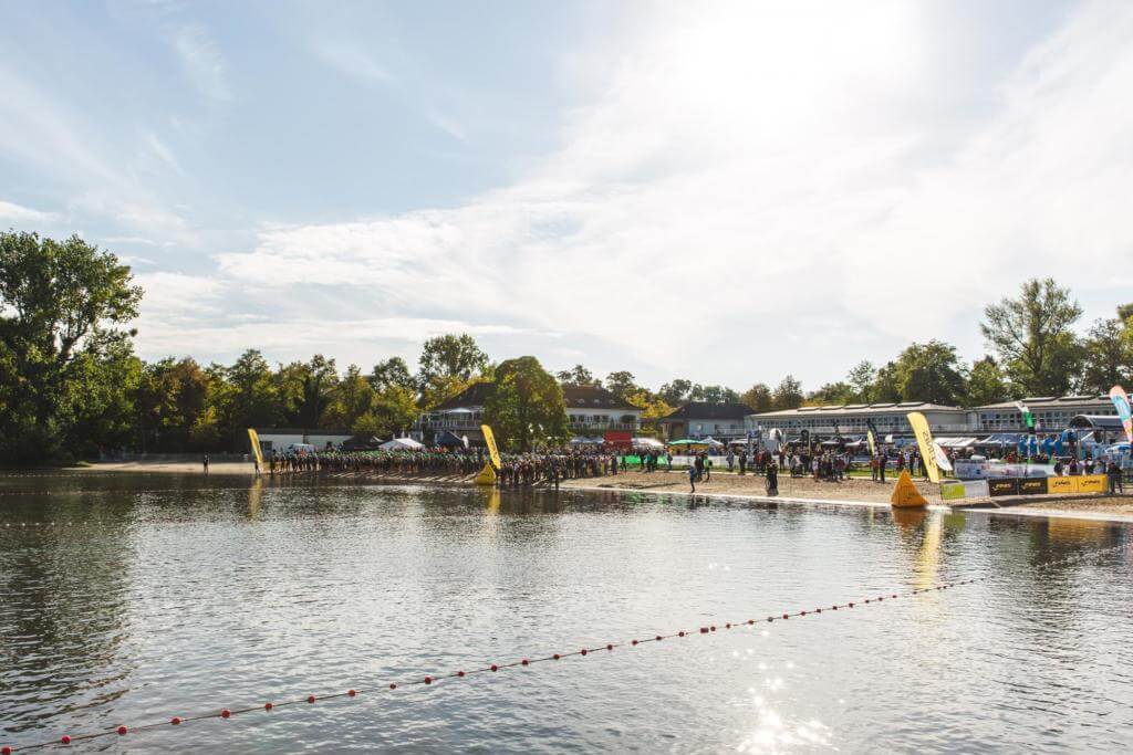 Maschsee in Hannover mit dem Startbereich des Triathlons am Ufer und einer Bojenleine im Wasser