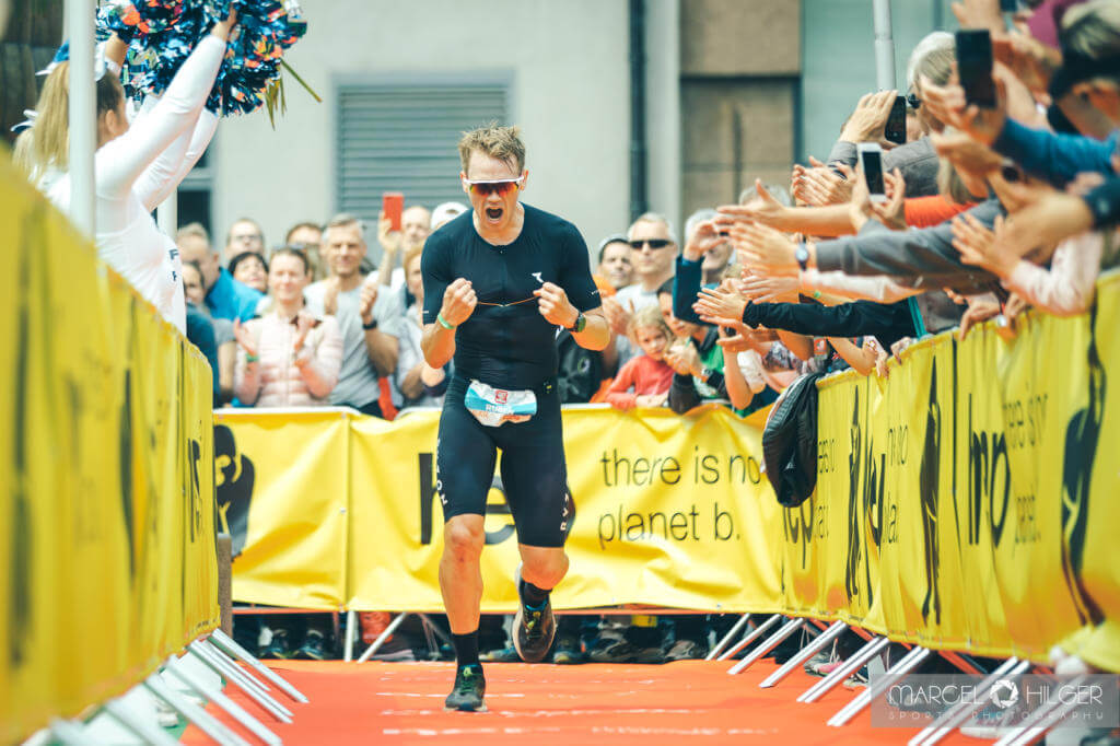 Ruben Zepuntke jubelt mit geballten Fäusten im Zielkanal der Challenge Heilbronn 2019, Zuschauer applaudieren