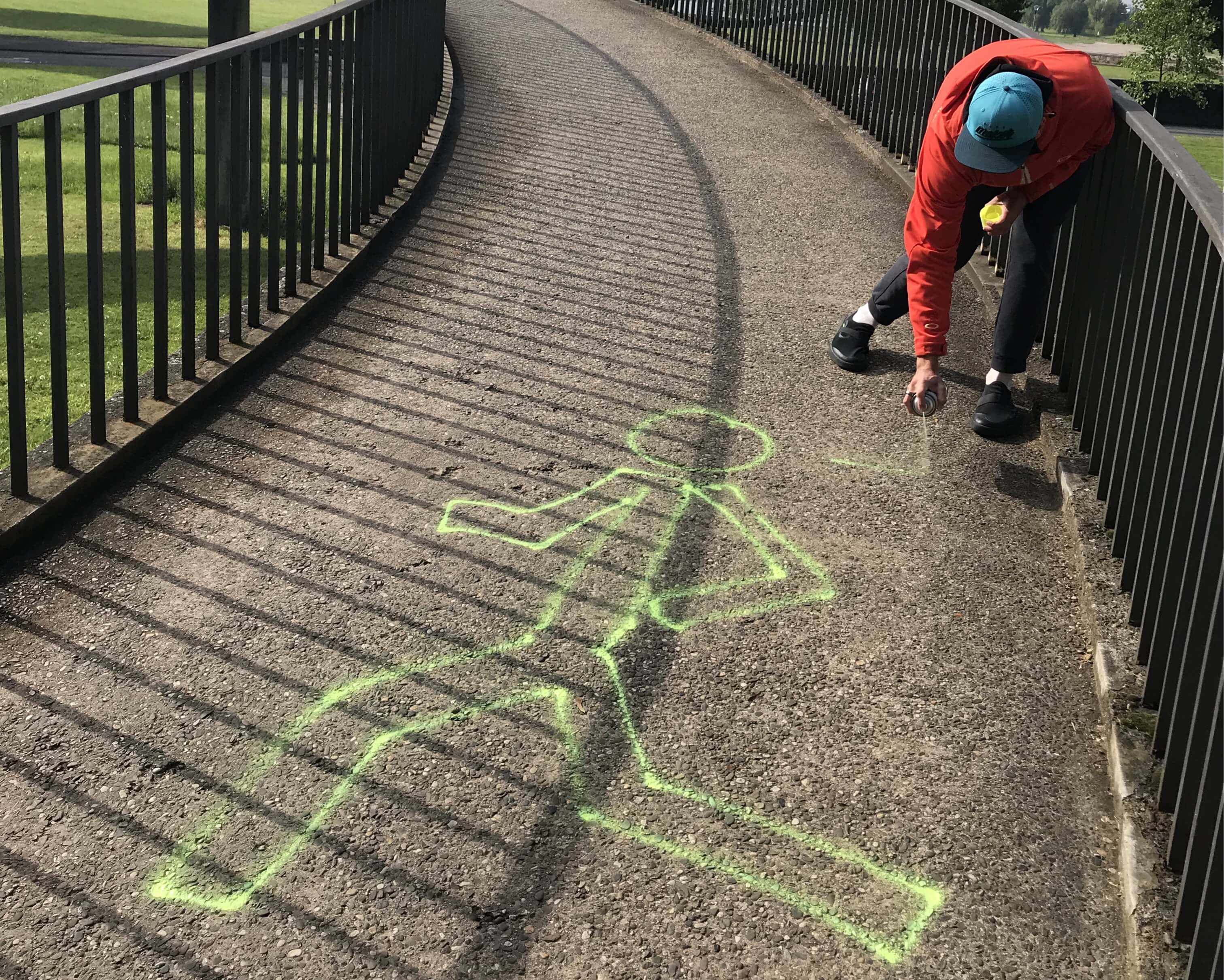 Helfer sprüht ein neongelbes Strichmännchen als Streckenmarkierung für den Wings for Life App Run Düsseldorf