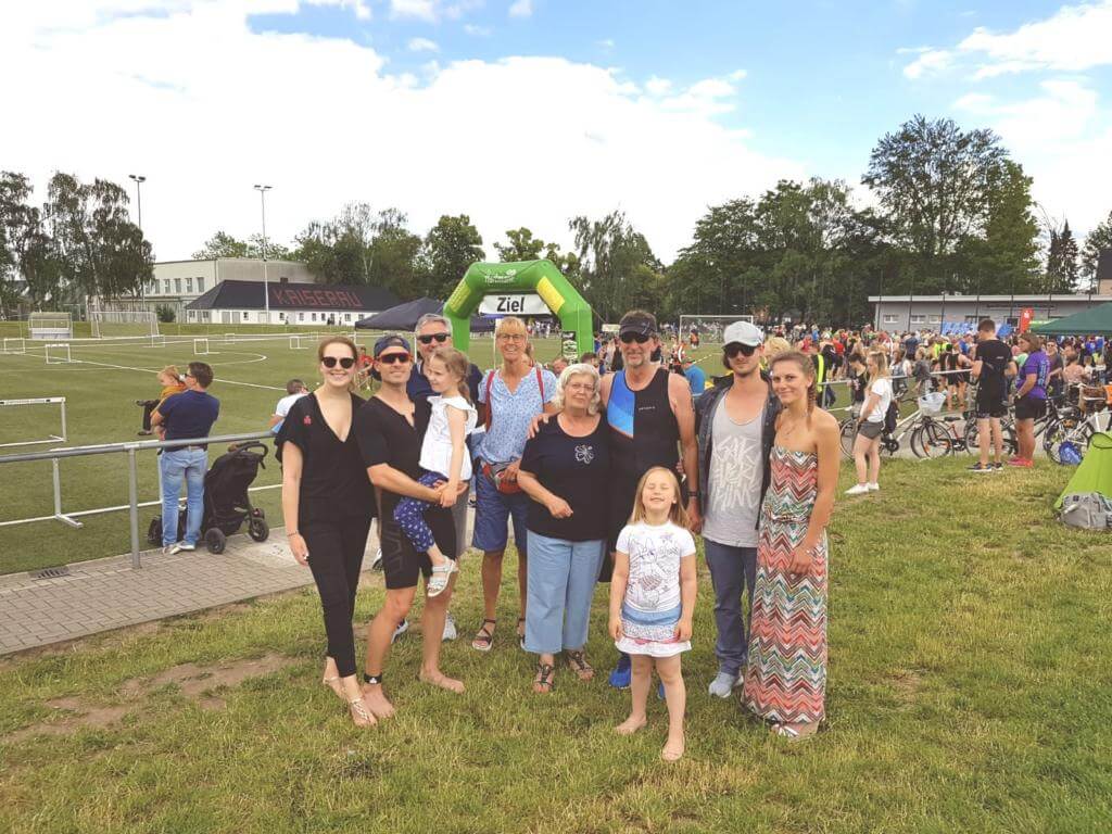 Gruppe aus Erwachsenen und Kindern vor dem Zielbogen einer Breitensportveranstaltung am Sportplatz