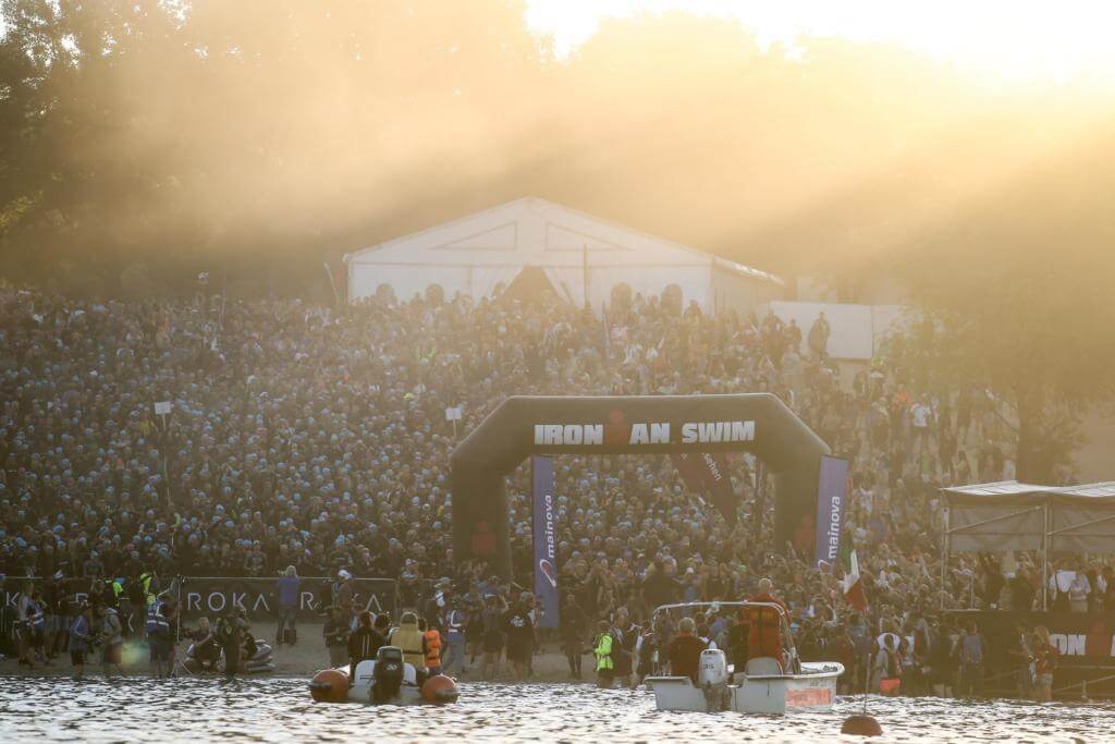 Tausende Athleten im Neoprenanzug warten im Morgendunst am Langener Waldsee auf den Schwimmstart des Ironman Frankfurt