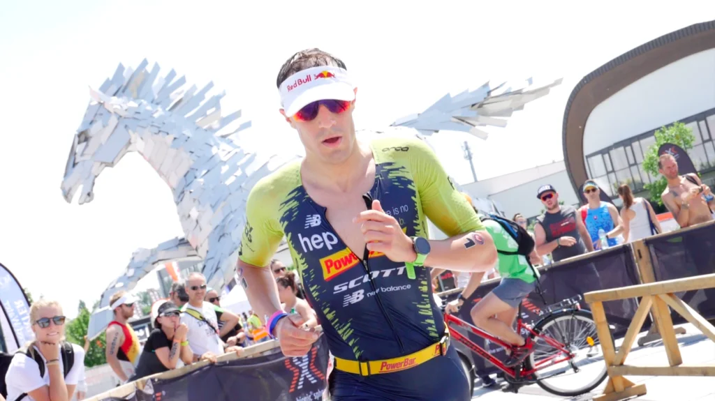 Triathlet mit weißem Visor und Sonnenbrille auf der Laufstrecke von The Championship in Šamorín vor einer Pferdeskulptur