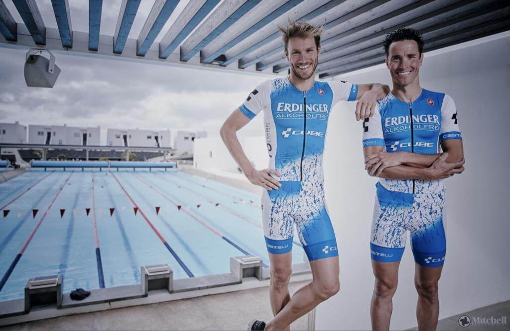 Die Brüder Andreas und Michael Raelert in Erdinger-Einteilern posieren am Rand eines Schwimmbeckens