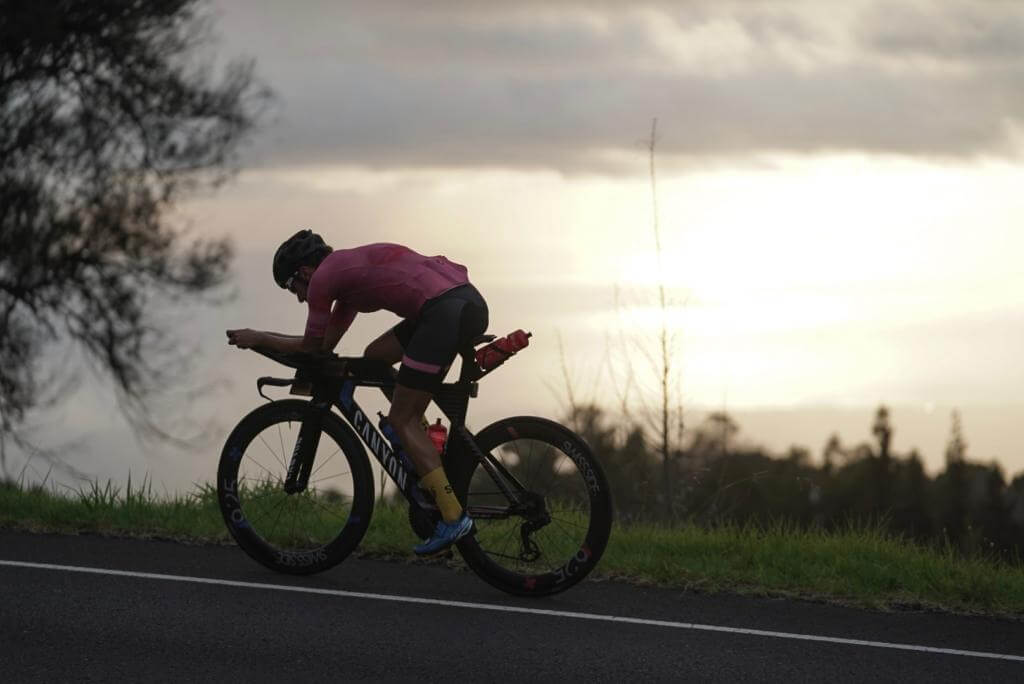 Triathletin im pinken Trikot auf einem Canyon-Zeitfahrrad im Abendlicht beim Training auf Maui