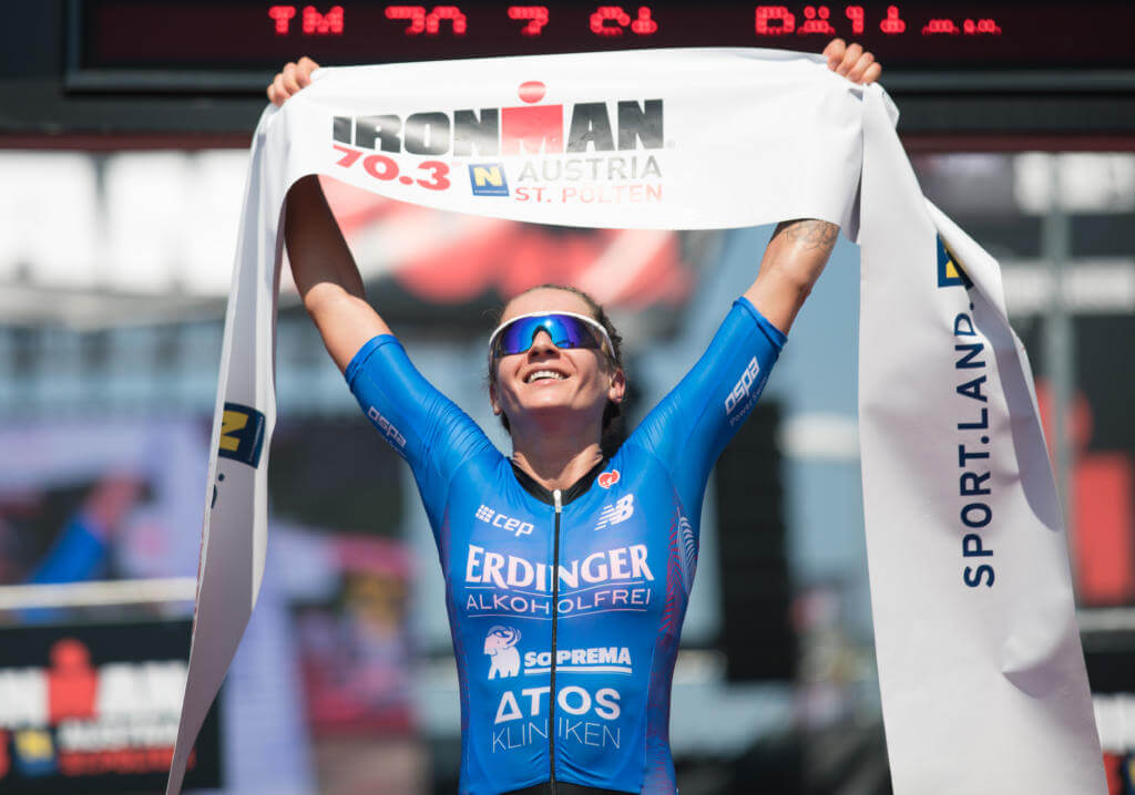 Laura Philipp hält im Ziel des Ironman 70.3 Austria in St. Pölten jubelnd das Zielband hoch