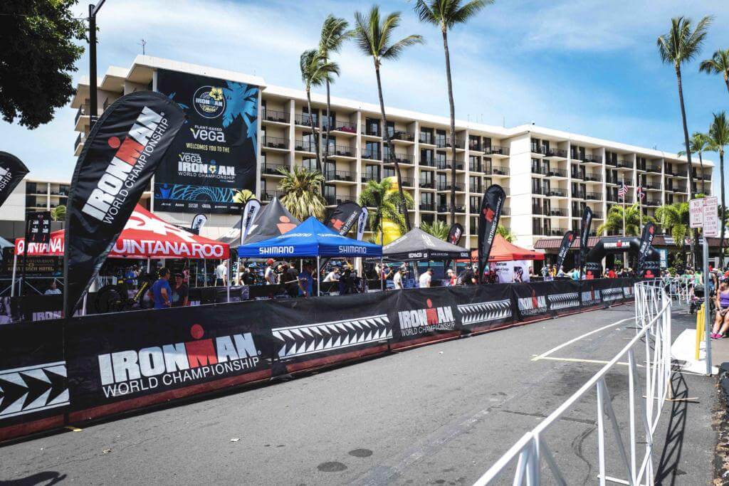 Rennstrecke in Kailua-Kona mit Bannern der Ironman World Championship, Sponsorenzelten und Hotel am Renntag 2019