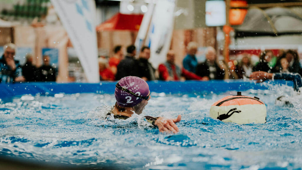 Schwimmer mit lila Badekappe und Boje im Messebecken bei den motrivation days der Freizeit Messe Nürnberg