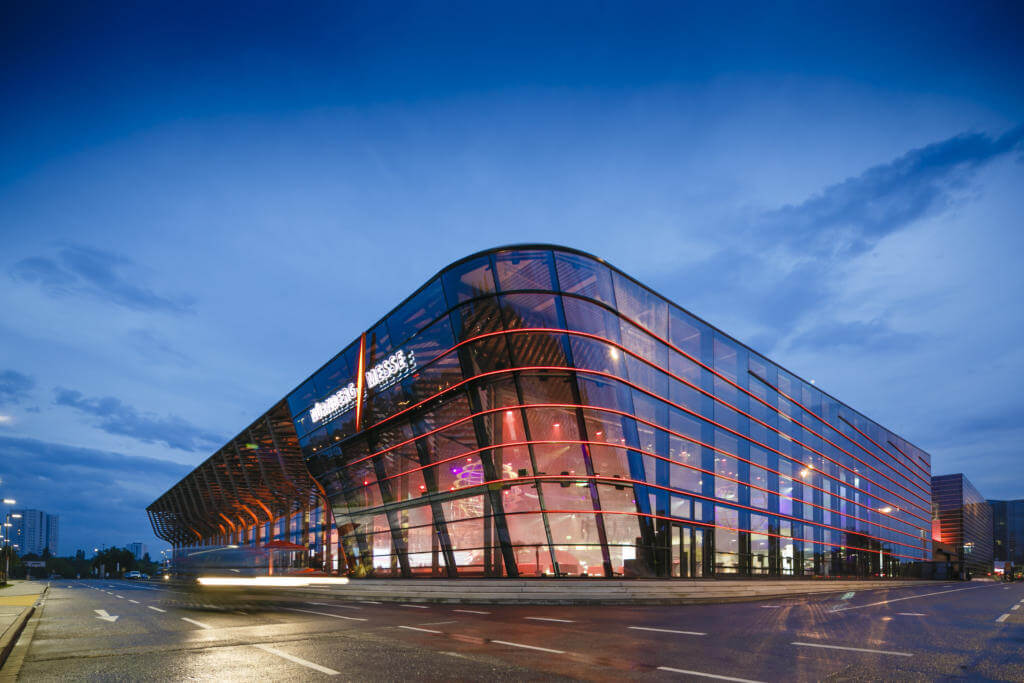 Halle 3A der NürnbergMesse mit beleuchteter Glasfassade in der Abenddämmerung