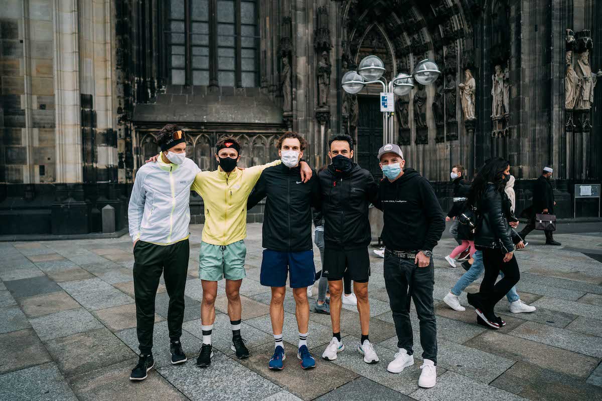 Gruppe mit Masken posiert nach dem Ultralauf von Koblenz nach Köln vor dem Portal des Kölner Doms