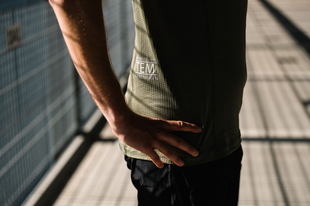 Detail des olivgrünen TEM Running T-Shirts von Fe226 mit Logo TEM København an der Seite
