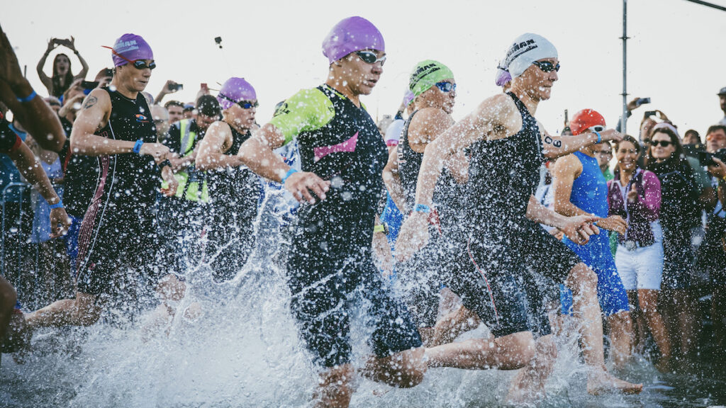 Frauen sprinten bei einem Landstart eines Triathlons ins Wasser