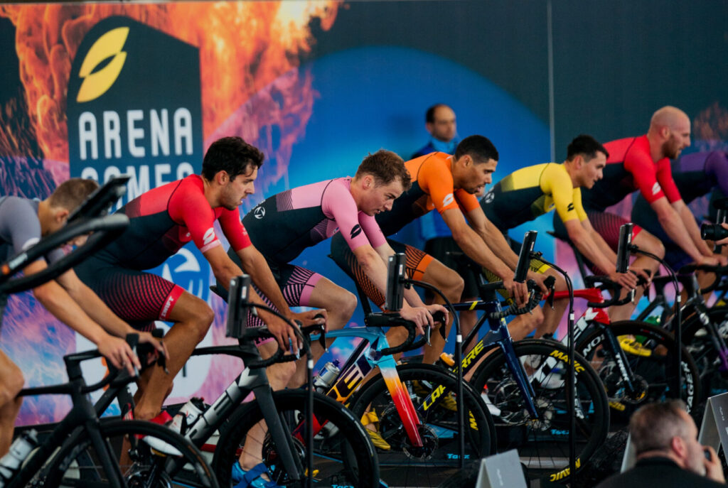 Triathleten in bunten Einteilern auf Radtrainern beim virtuellen Radrennen der Arena Games in München