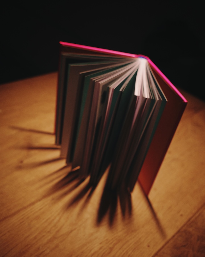 Aufgefächertes Buch Die Kunst des Triathlons steht aufrecht auf einem Holztisch im Streiflicht